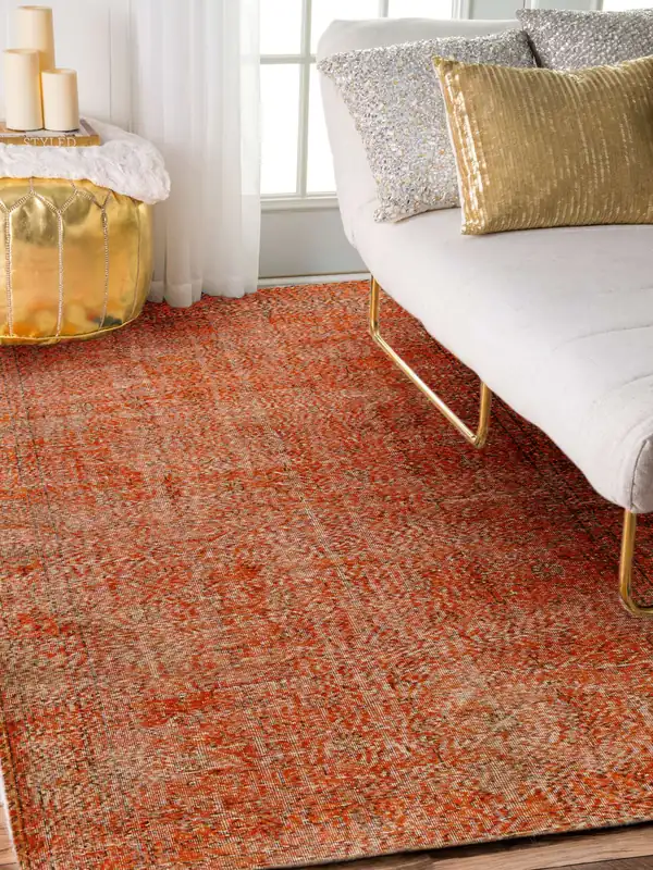 An orange overdyed carpet beside a white sofa
